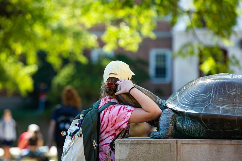 student hugs testudo statue